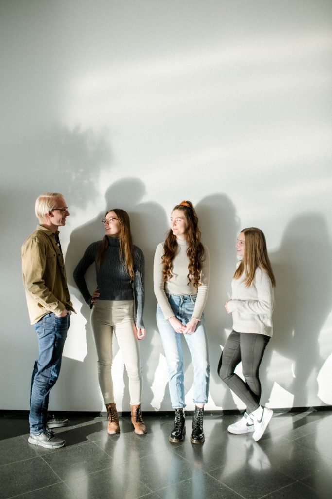 Four students standing side by side in front of a white wall