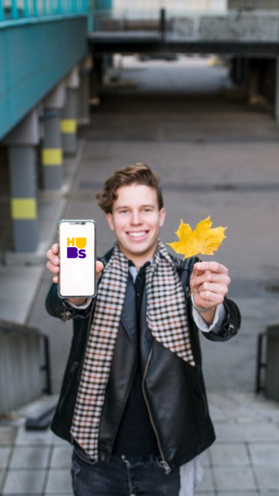 A standing man holding a phone and a yellow maple leaf