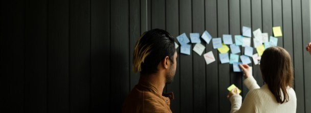 Students working with colourful post-it notes in front of a black wall