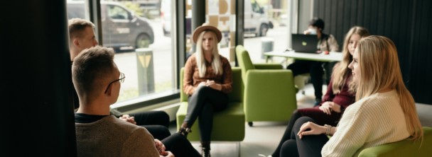 People sitting on chairs in a circle, discussing.