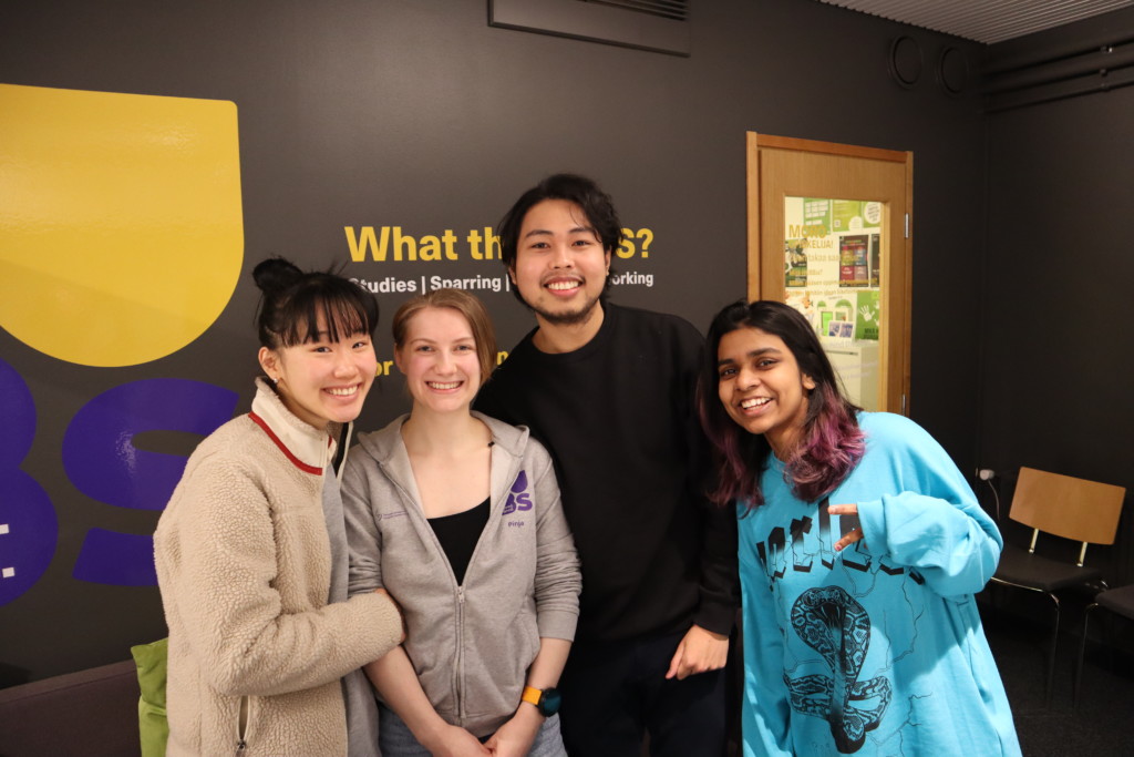 Four people smiling and standing side by side at HUBS premises on campus.