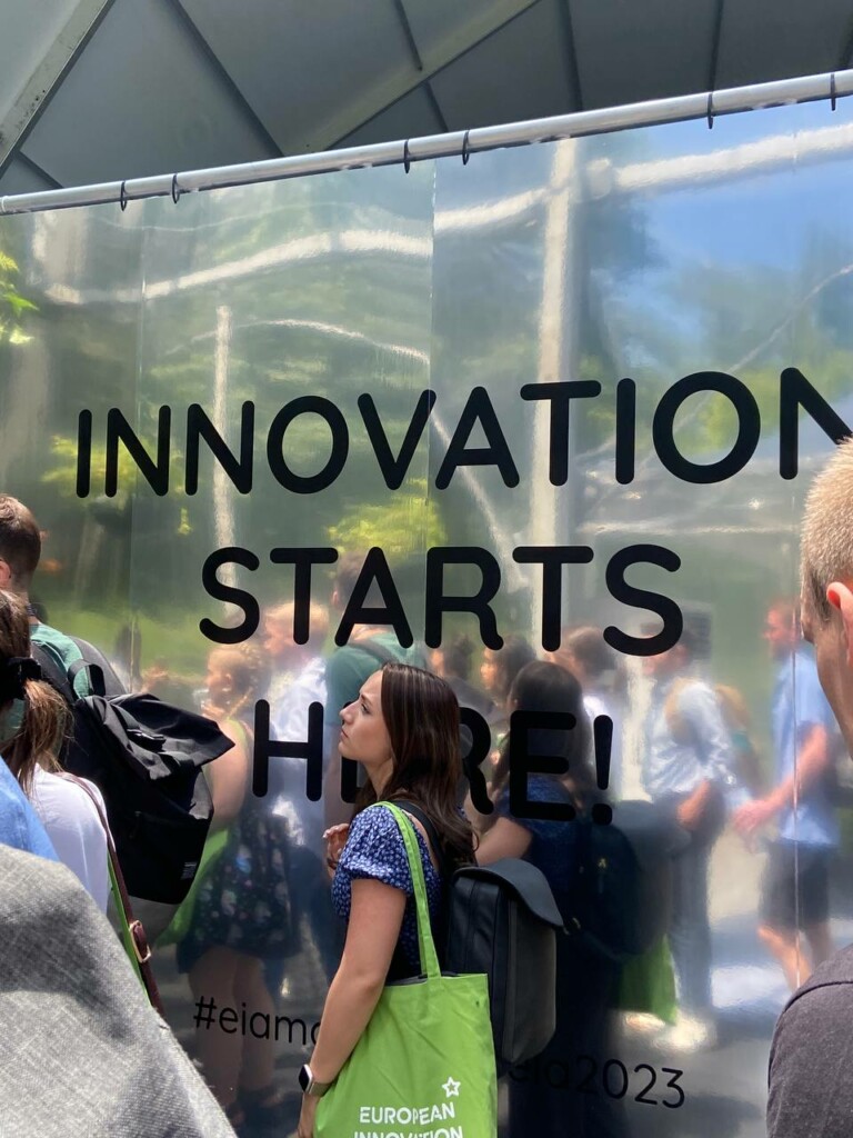 A woman standing in front of a text "INNOVATION STARTS HERE".