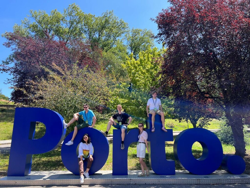 FIve people sitting on top of big letters that type out Porto.